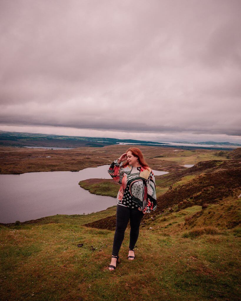 Woman in a colourful top standing on a hill at Lough Salt and enjoying the views over County Donegal Ireland