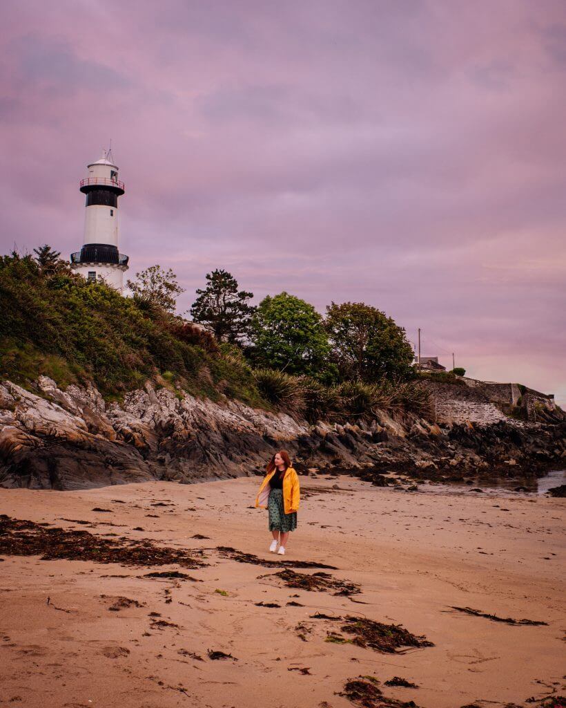 Women wearing a yellow raincoat walking around the base of Stroove lighthouse at Inishowen peninsula in County Donegal Ireland
