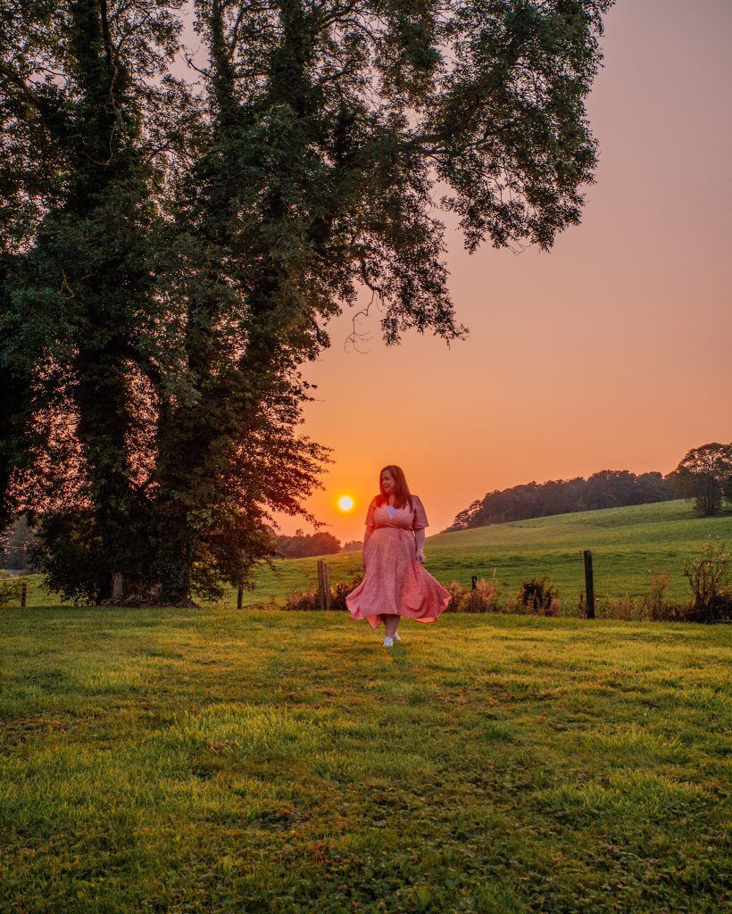 Woman in a red dress walking in the gardens of Loughcrew Lodge at sunset on a unique Irish staycation