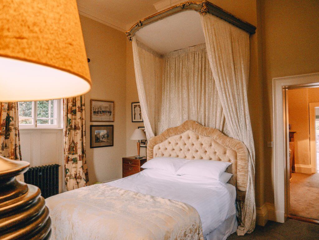 Bedroom with antique furnishings and lace bed canopy at Loughcrew Lodge a unique stay in Ireland