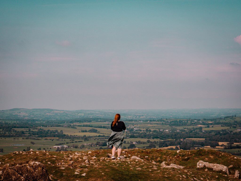 Woman in a green dress standing at the stone circles in Loughcrew cairns in Meath