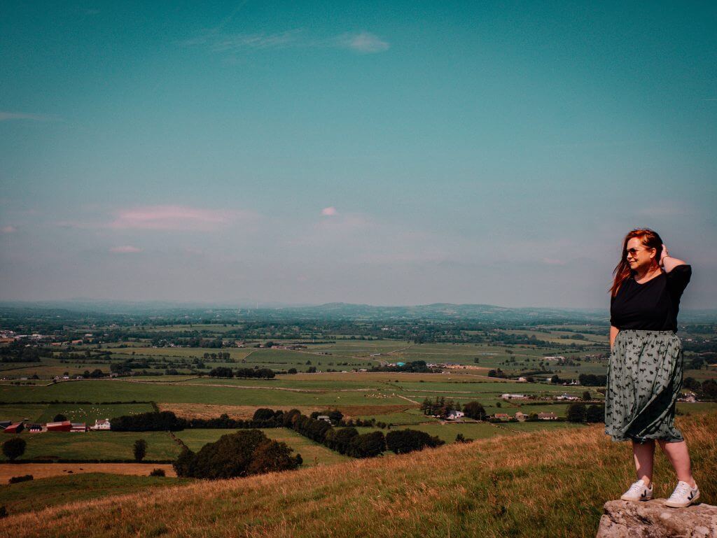 Woman in a green skirt looking out over the views at Loughcrew Cairns in Ireland