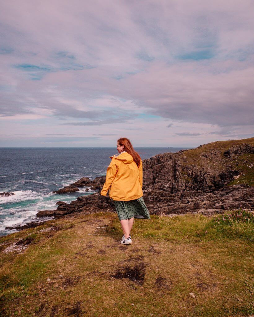 Woman in a yellow raincoat looking at the views at Malin Head in County Donegal
