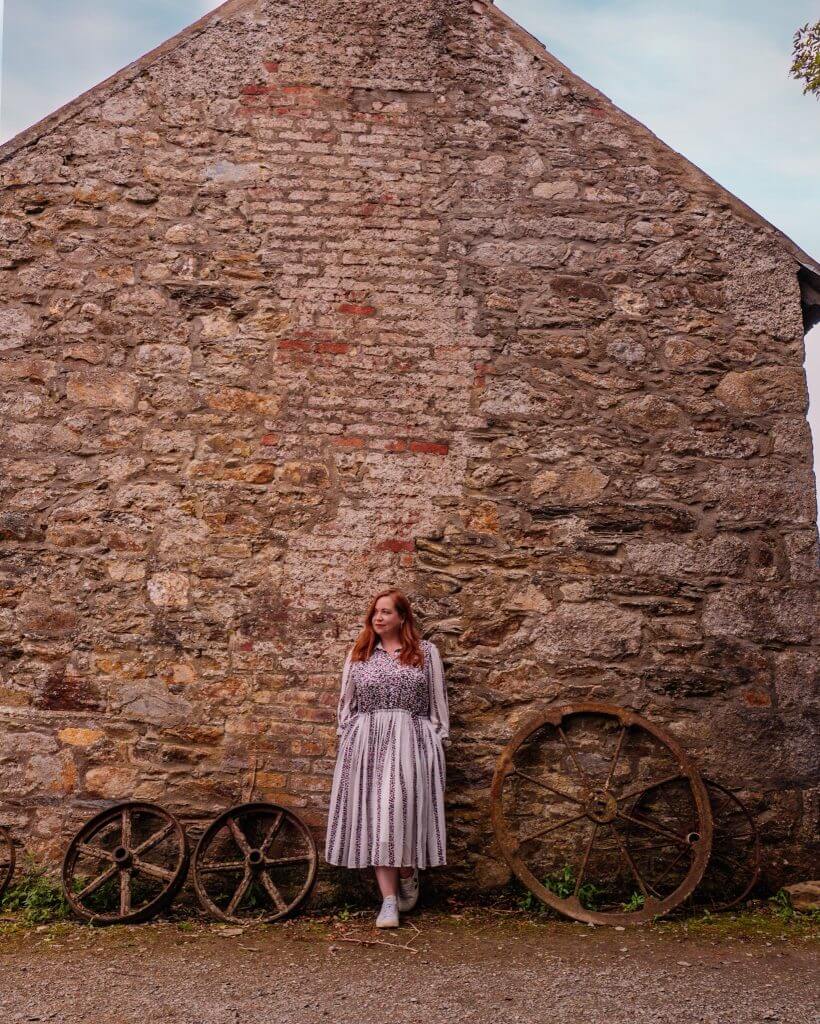 Woman standing against a barn at Greenan Maze in Wicklow Ireland on her staycation Ireland
