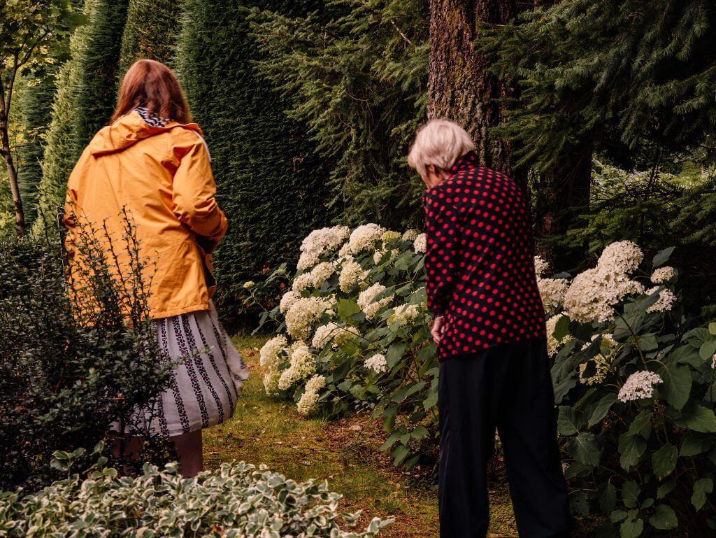 Elderly woman showing a younger woman in a yellow raincoat around Shekina Sculpture Garden in Wicklow Ireland