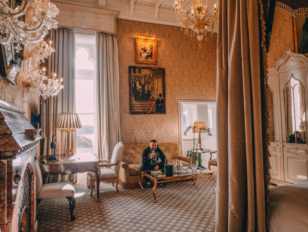 Man enjoying a glass of champagne in a luxurious bedroom at Ashford Castle