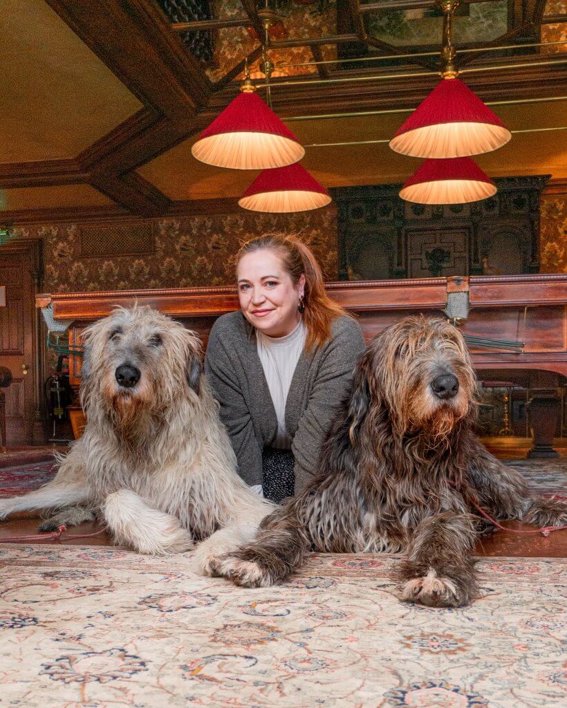 Woman sitting between two Irish wolfhounds at Ashford Castle Ireland, a luxury five star hotel