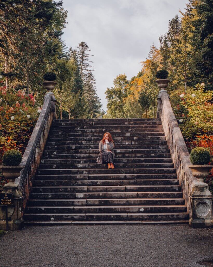 Woman sitting on stone steps at Ashford Castle a luxury hotel in Ireland
