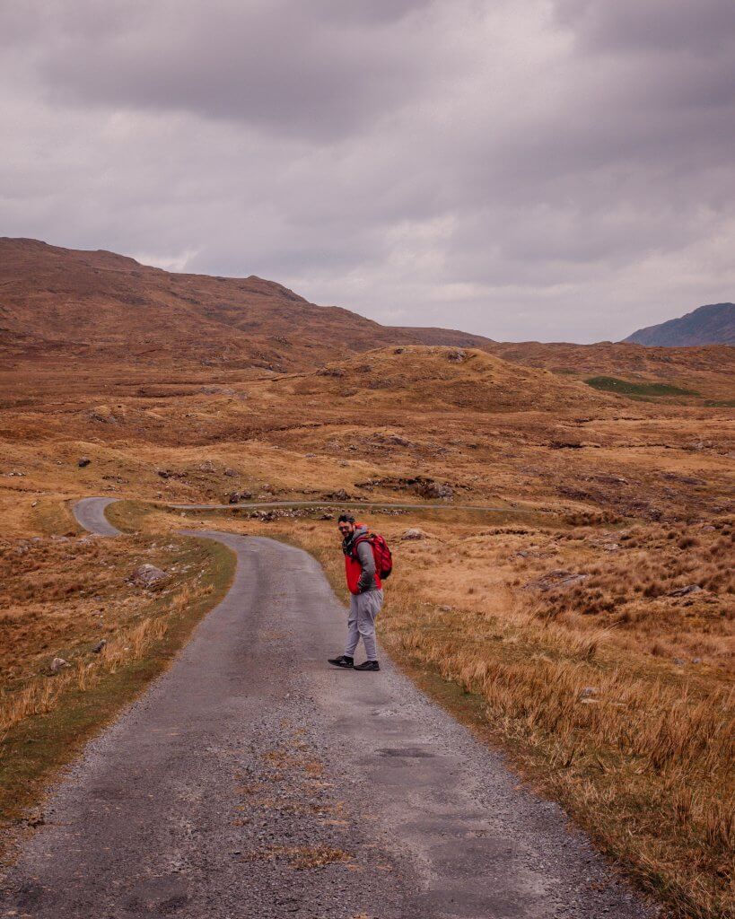 Man in a grey tracksuit and red rain jacket hiking on a walking trail in Connemara Ireland