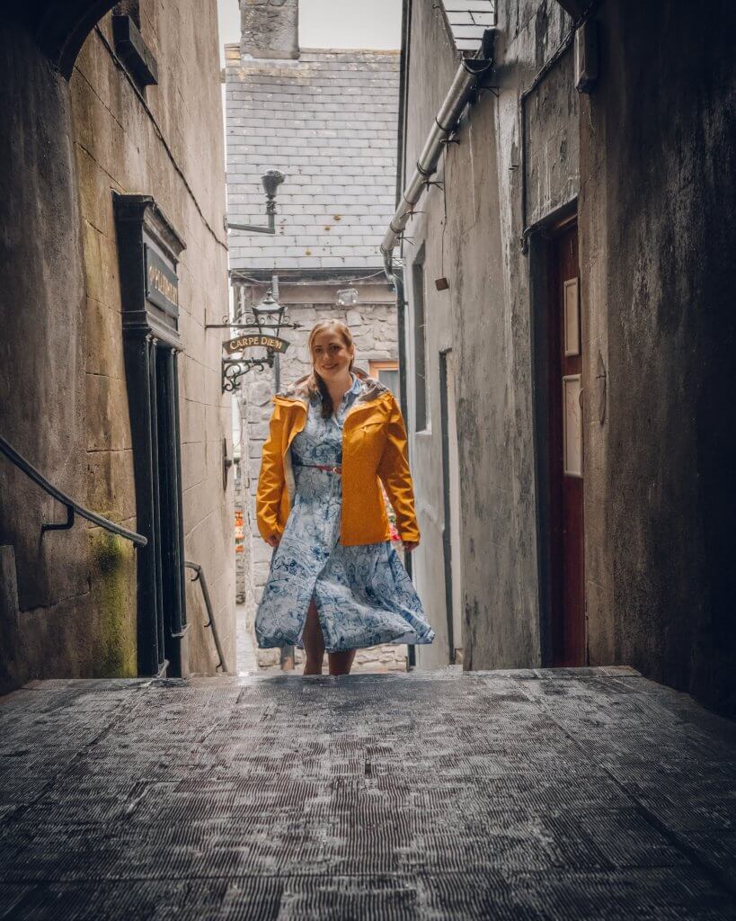 Woman in a yellow raincoat walking through the medieval streets of Kilkenny Ireland