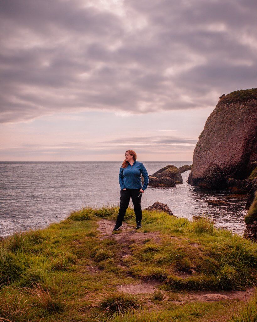 Woman wearing black trousers and a blue top exploring the Antrim coastline