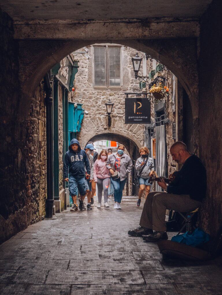 Narrow streets of Kilkenny Ireland with a busker playing a guitar on it