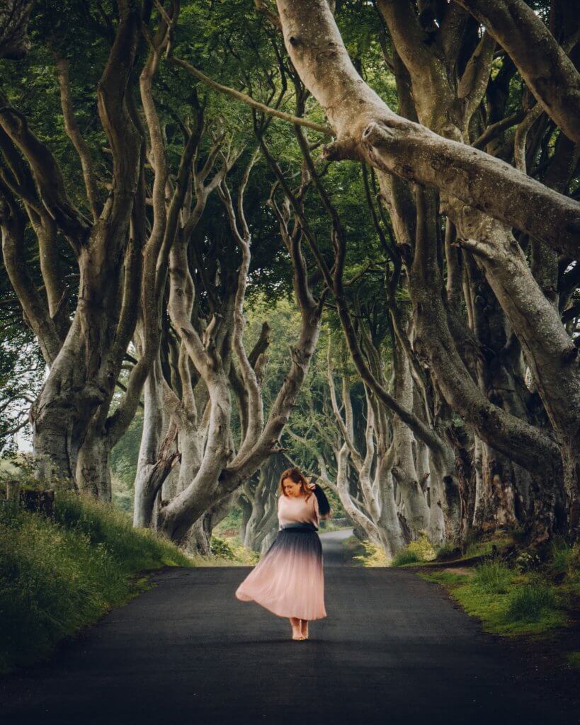 Woman with lyme disease in a pink dress at The Dark Hedges in Antrium the ultimate Game of Thrones filming location