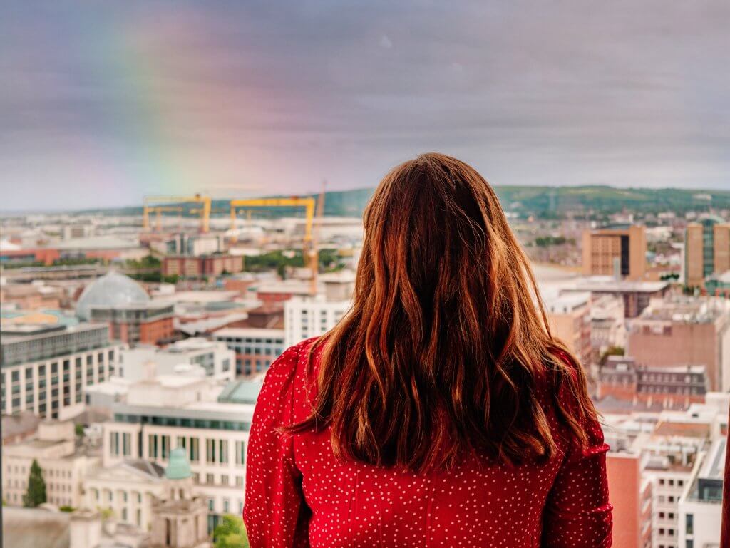 Woman in a red dress looking at the views of Belfast city from the Observatory Bar in The grand central hotel Belfast