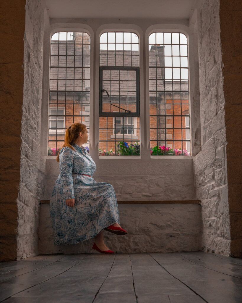 Woman in a blue dress sitting on a window sill at Rothe House and gardens in Kilkenny Ireland