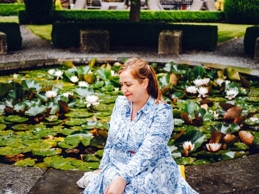 Woman in a blue dress sitting at a lily pond in Butler House Kilkenny