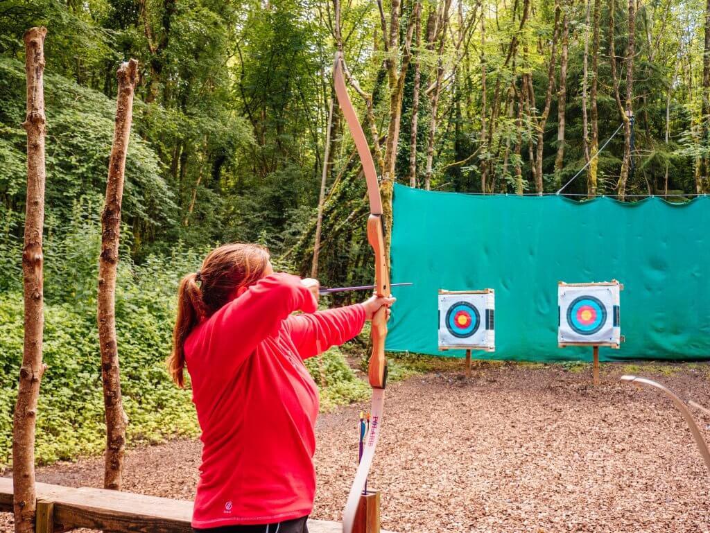 Woman in a red top holding an archery bow at Castlecomer Discovery Park Kilkenny