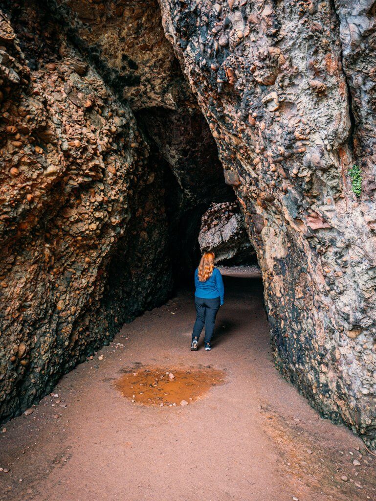 Woman wearing black trousers and a blue top at Cushendun caves in Antrim Northern Ireland
