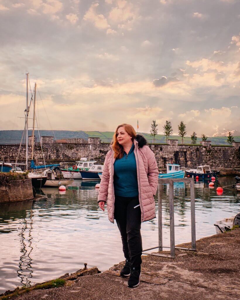 Woman in a pink coat standing at Carnlough Harbour