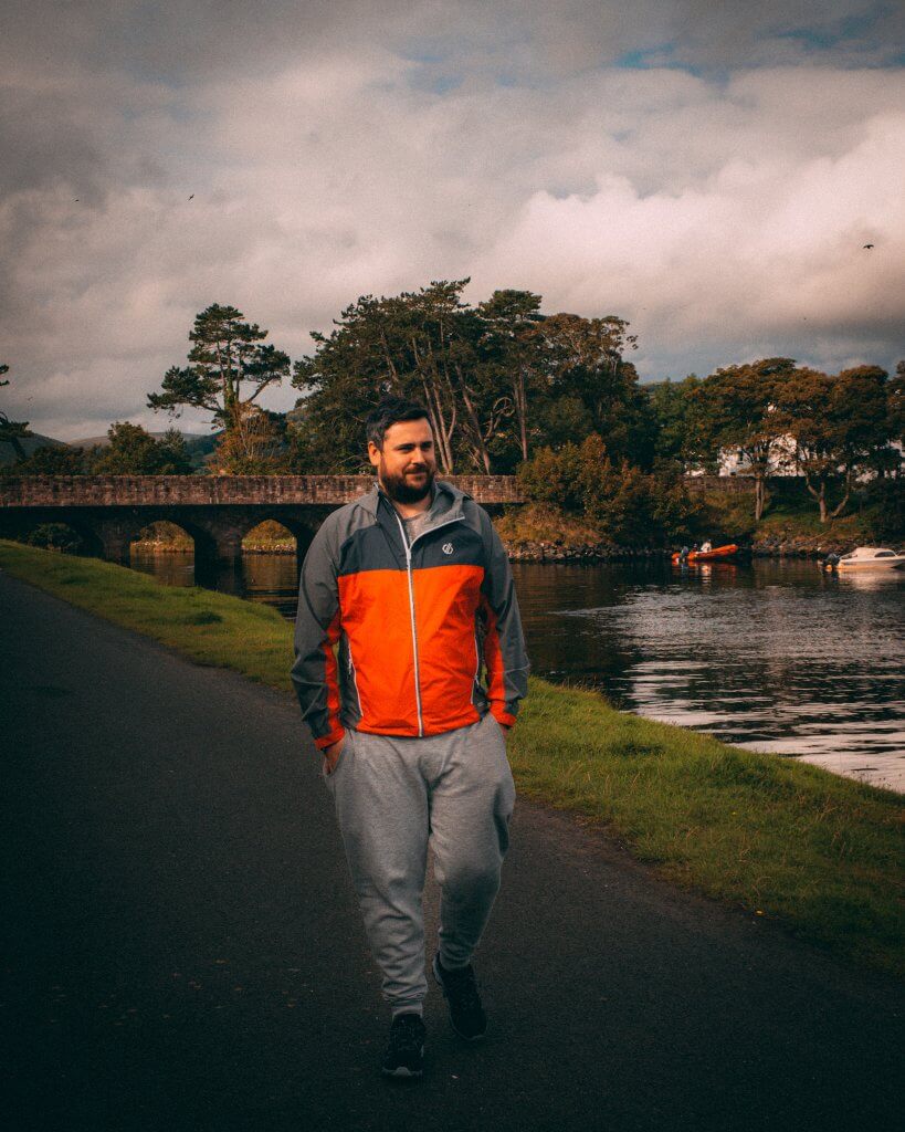Man in an orange jacket walking along the harbour at Cushendun in Antrim Northern Ireland