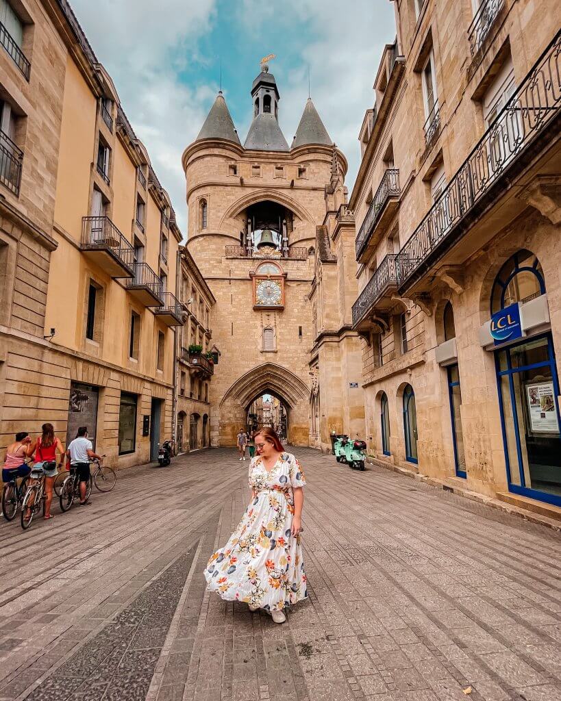 Woman in a floral dress walking in front of the Grosse cloche in Bordeaux France