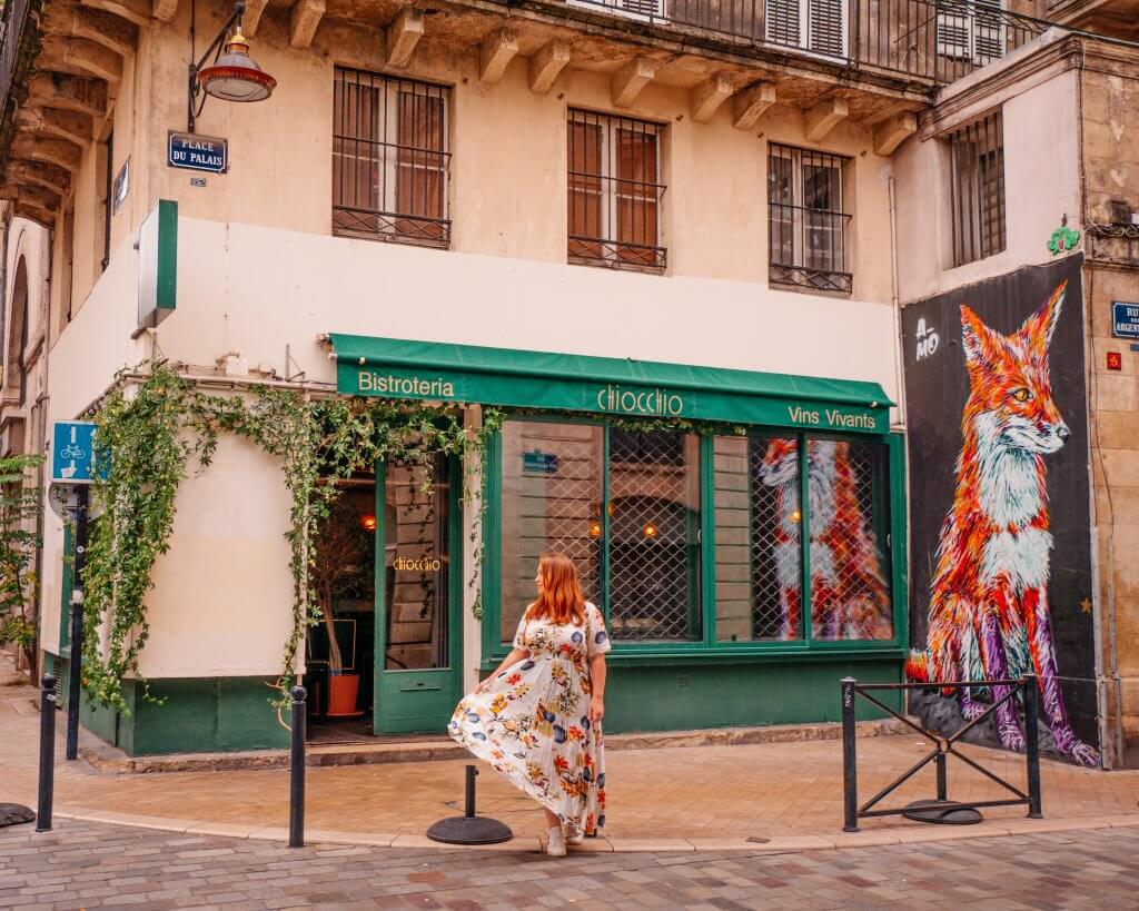 Woman walking in front of a restaurant and fox mural in Bordeaux France