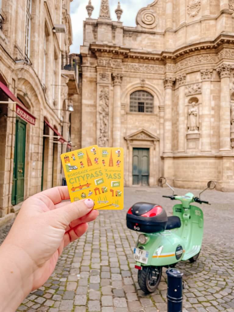 Woman holding up two Bordeaux city passes perect for your Bordeaux itinerary when you are exploring Bordeaux