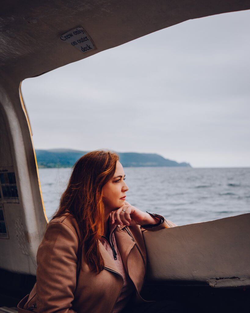 Woman sitting on a boat in Carnlough Harbour a hidden gem in Antrim