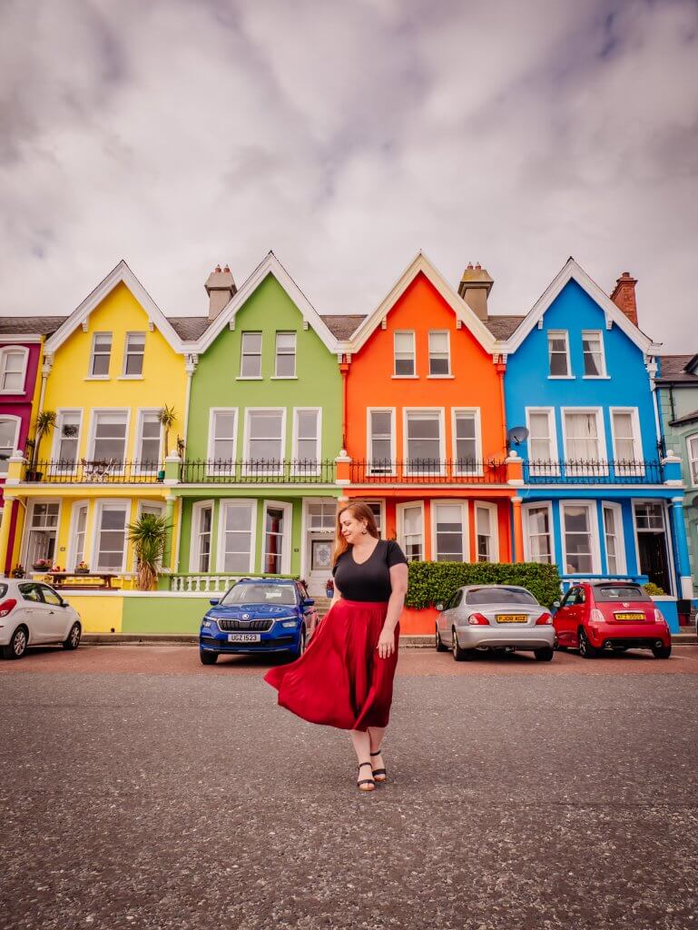 Woman standing in front of the colourful houses in Whitehead County Antrim