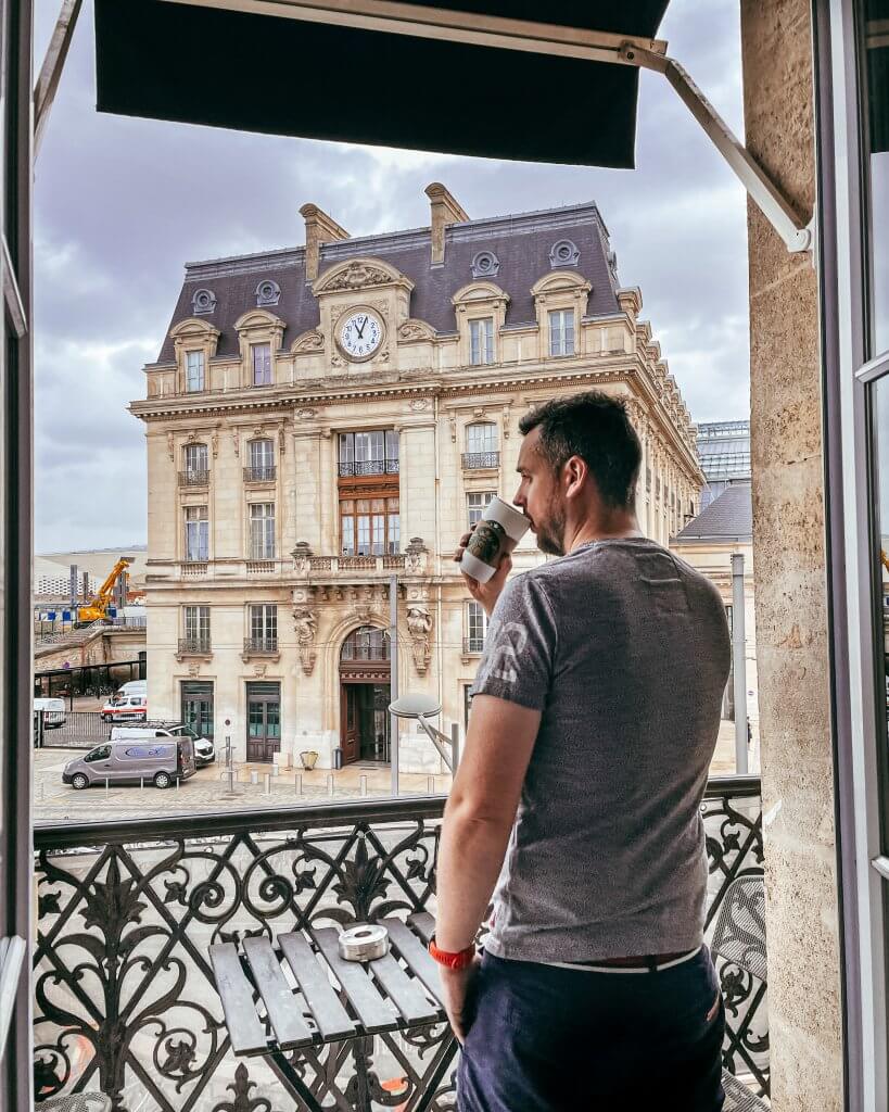 Man drinking coffee with a view of Gare St Jean train station on a 2 day Bordeaux itinerary