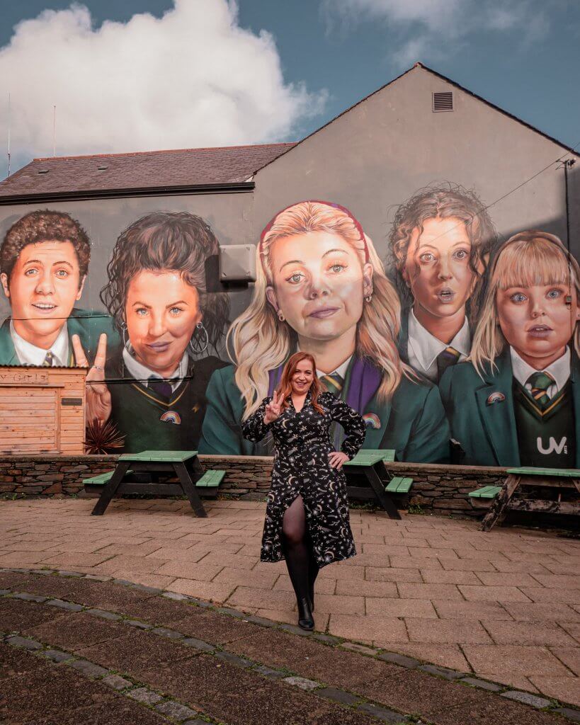Woman standing at the Derry Girls mural in Derry Northern Ireland