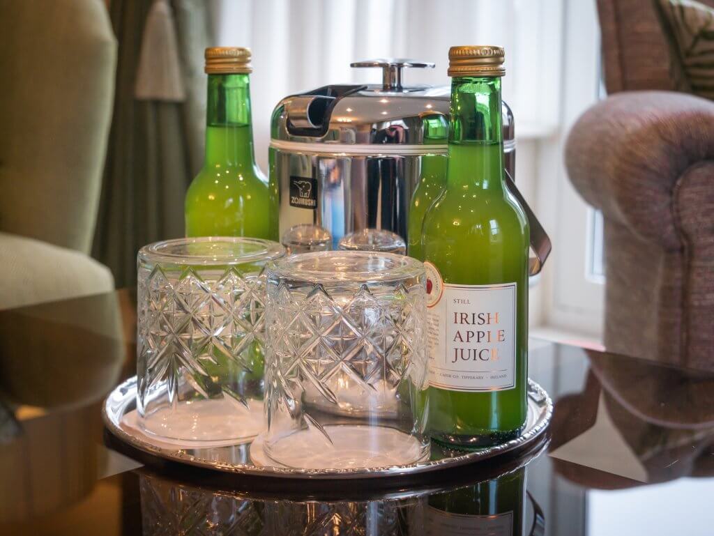 Irish apple juice and crystal glasses are laid out on a table in a Signature Suite in Sheen Falls, Lodge, Kenmare, Ireland.