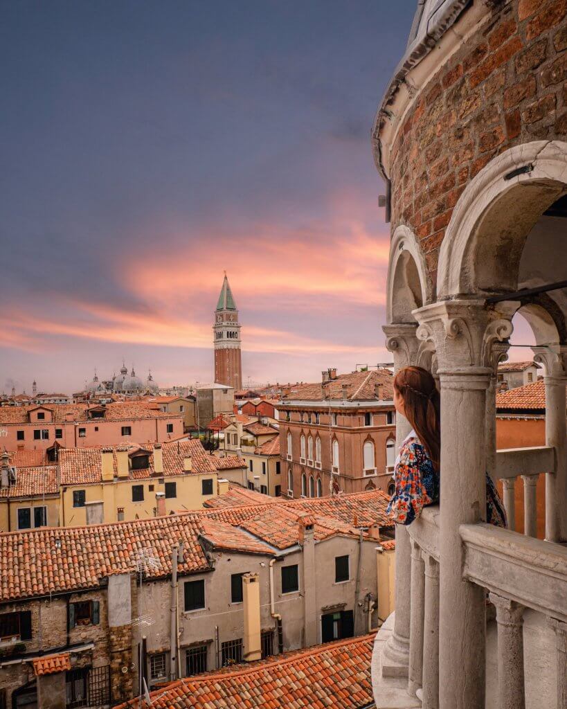 Woman looking at a rooftop view of Venice Italy from the viewing point Scala Contarini del Bovolo