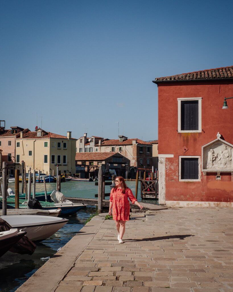 Woman in a red dress walking along the canals on San Pietro Island in Castello Venice