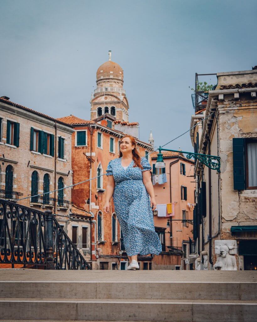 Woman in a blue dress walking over a bridge in Venice Italy