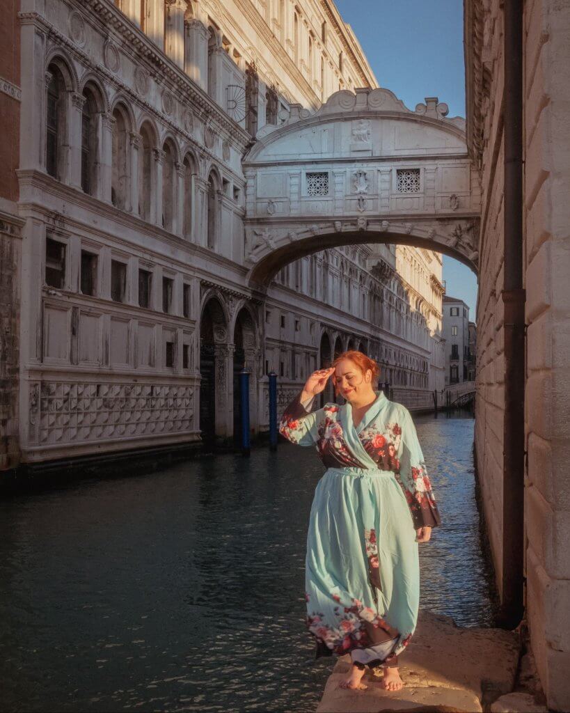 Woman in a long blue floral dress standing at the Bridge of Sighs in Venice Italy on of Venice's best Instagram spots