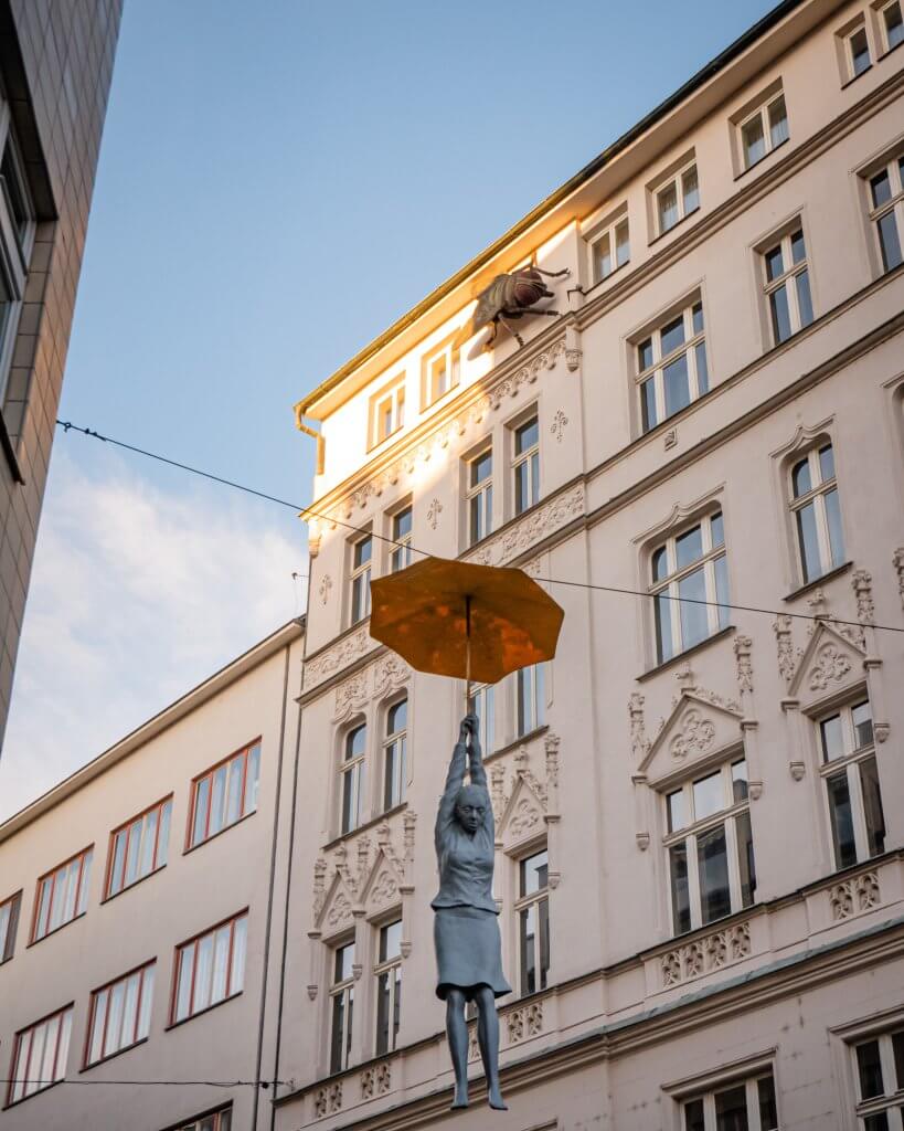 Michal Trpak woman hanging from umbrella at Mosaic House Design Hotel Prague