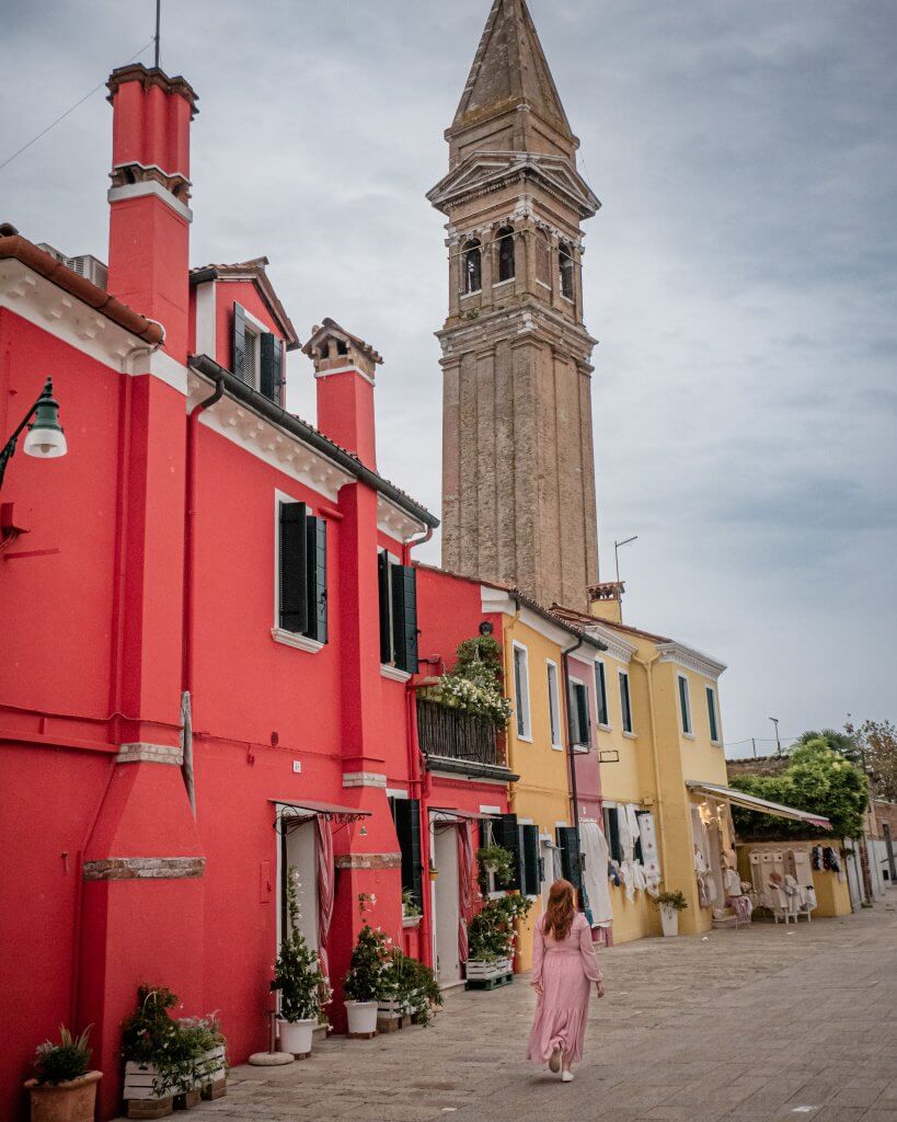 Woman walking beside the colourful houses in Burano Italy