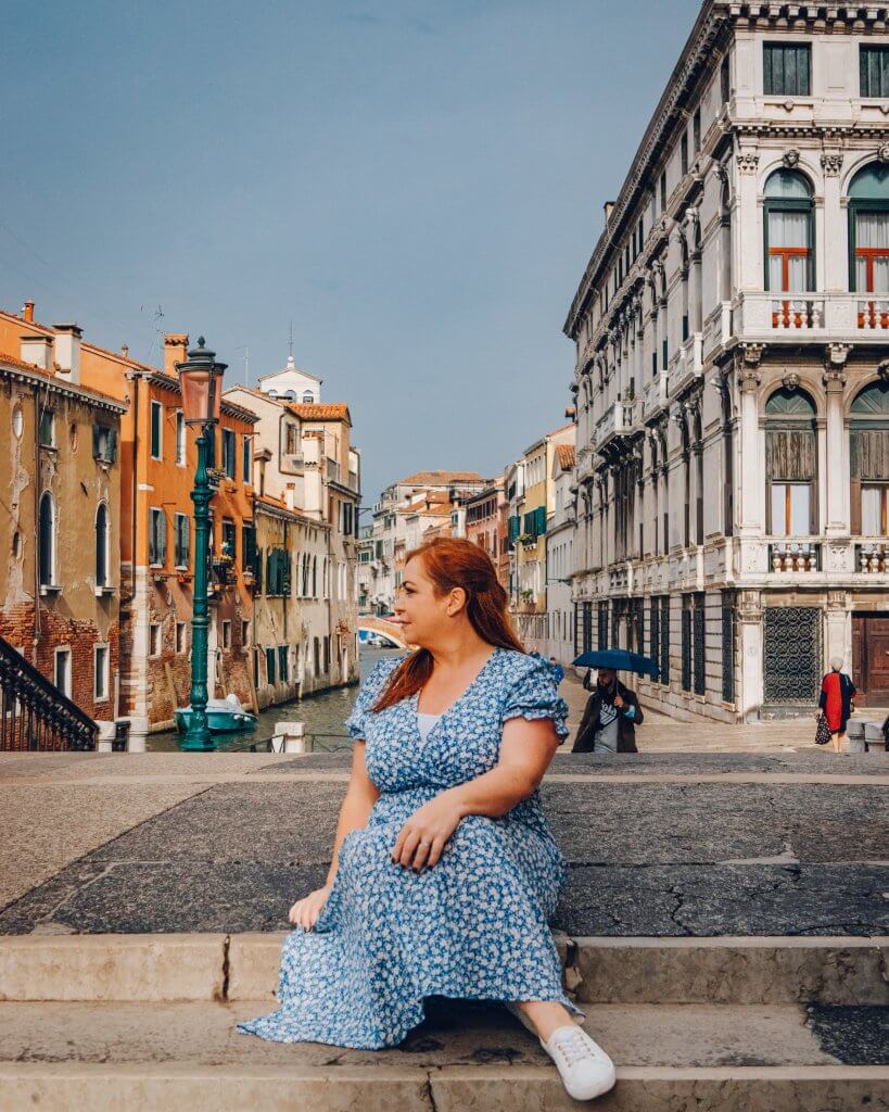 Woman sitting on the steps near a Venetian canal in Italy