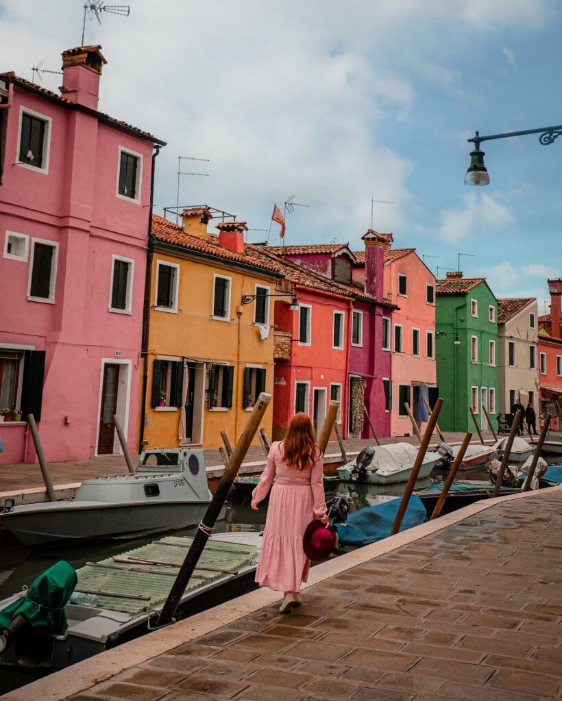 Woman walking along the canals and colourful houses of Burano Italy