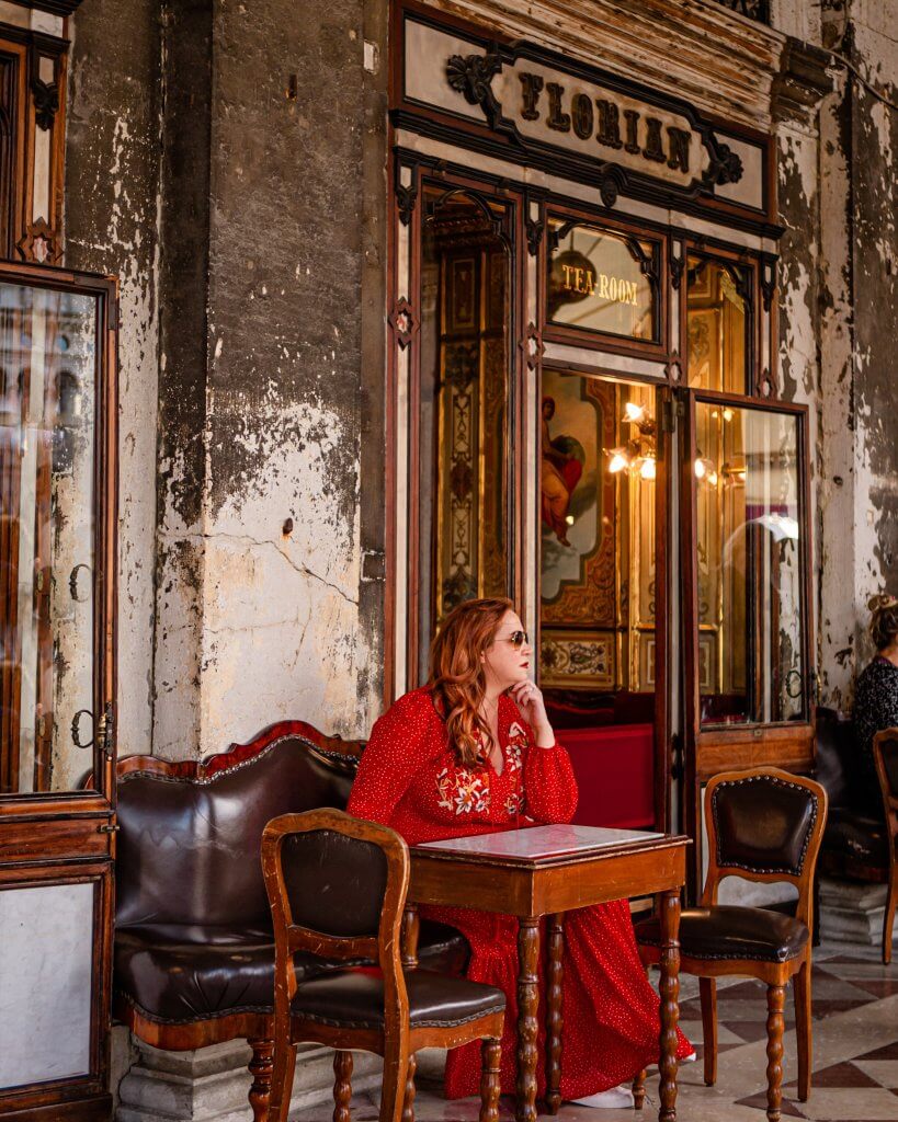 Woman in a red dress sitting at Caffe Florian in Venice one of the best Instagram spots in Venice