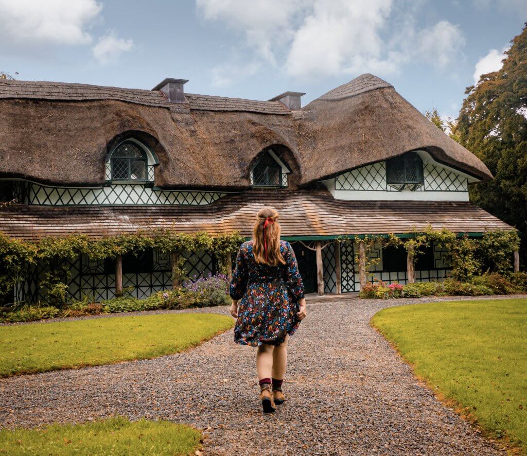Woman in a woodland pattern dress walking up the garden path at Swiss Cottage Cahir in Tipperary Ireland