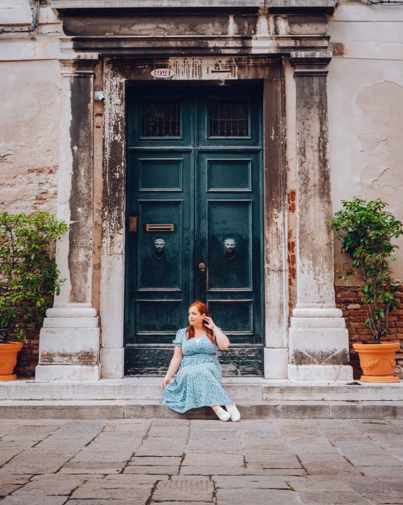 Woman in a blue dress sitting on a doorstep in Jesuit Square in Cannaregio Venice