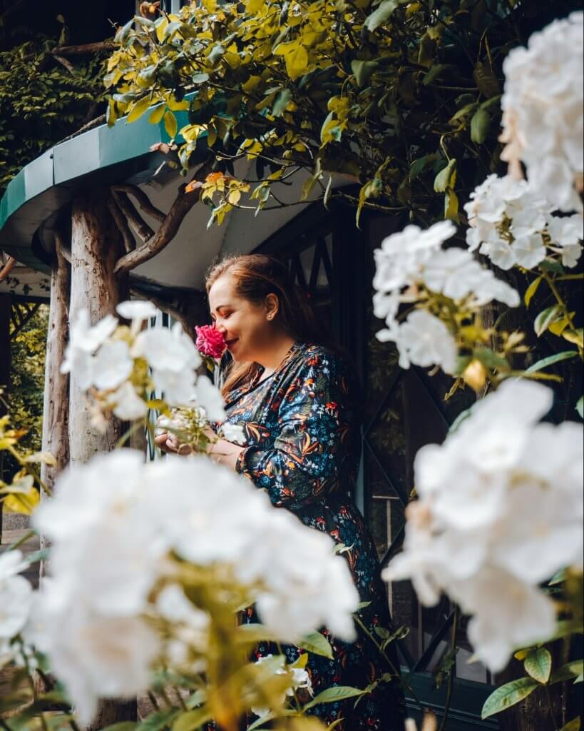 Woman smelling a rose surrounded by flowers at the Swiss Cottage in Cahir Tipperary Ireland