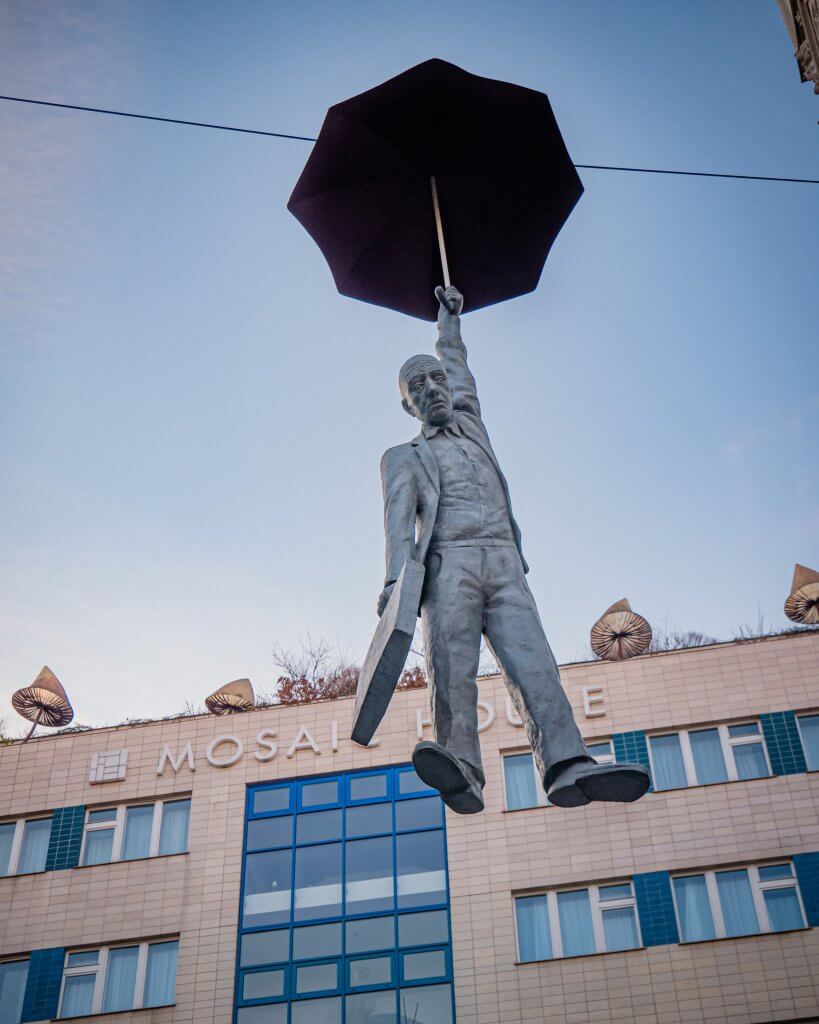 Man hanging from an umbrella statue in Prague Czech Republic