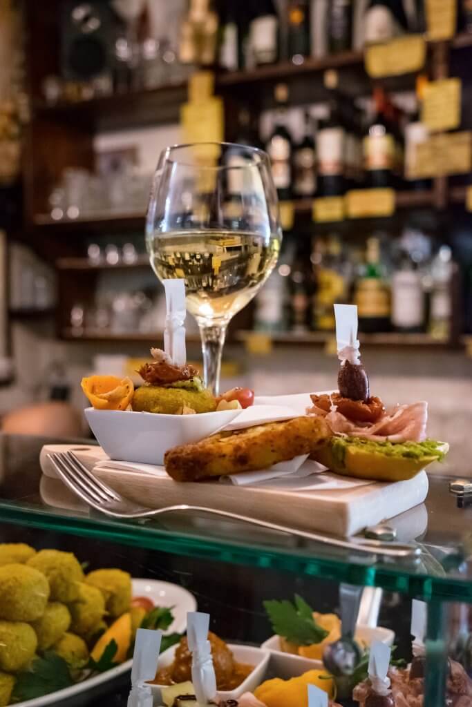 A glass of wine and a plate of Venetian Cicchetti traditional Venetian snacks