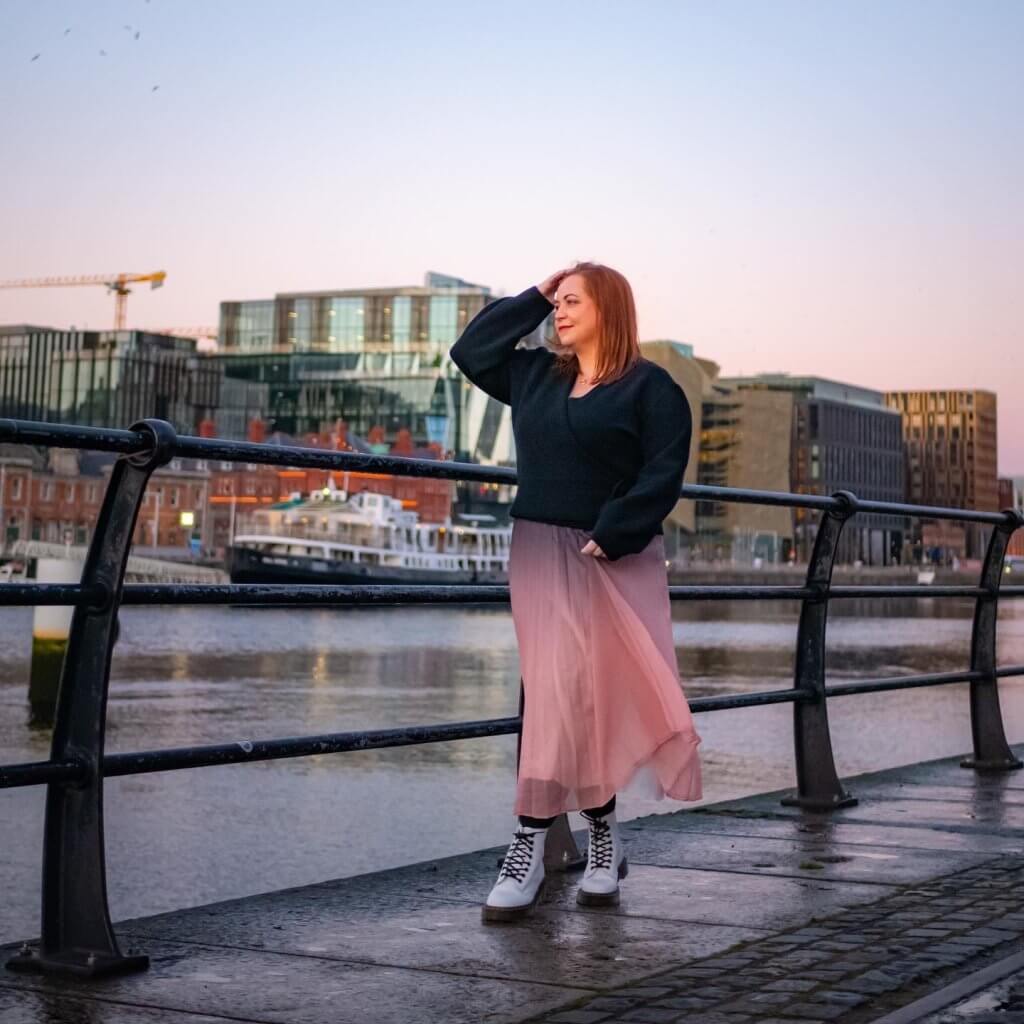 Woman in a pink skirt watching sunset at the Samuel Beckett Bridge in Dublin Ireland