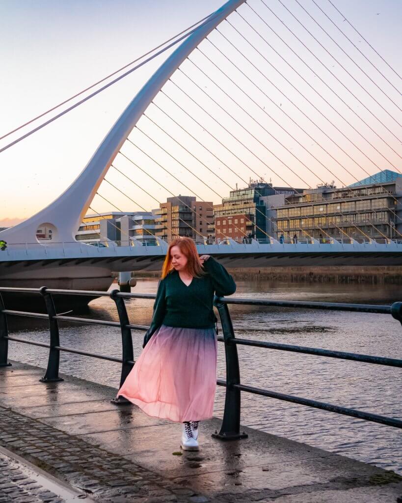 Woman in a pink skirt watching sunset at the samuel beckett bridge in Dublin Ireland