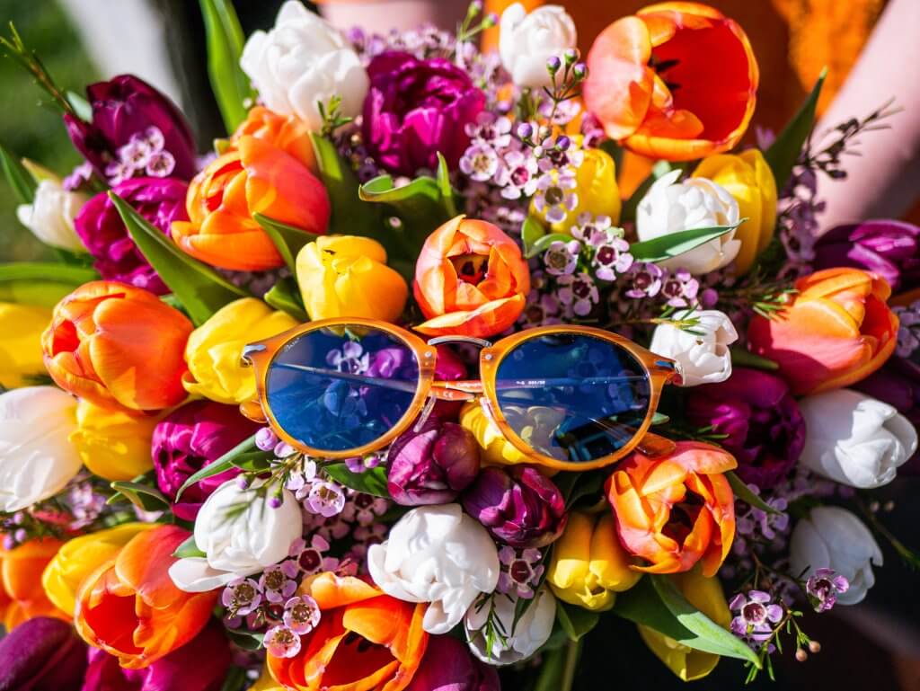 Persol sunglasses resting on a bouquet of flowers a travel must have