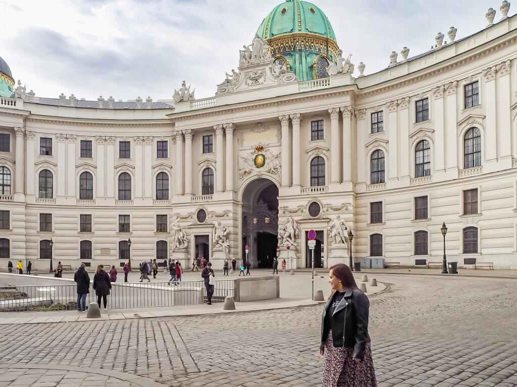 Woman walking around the grounds of Hofburg Palace in Vienna Austria the perfect thing to do during 3 days in Vienna.